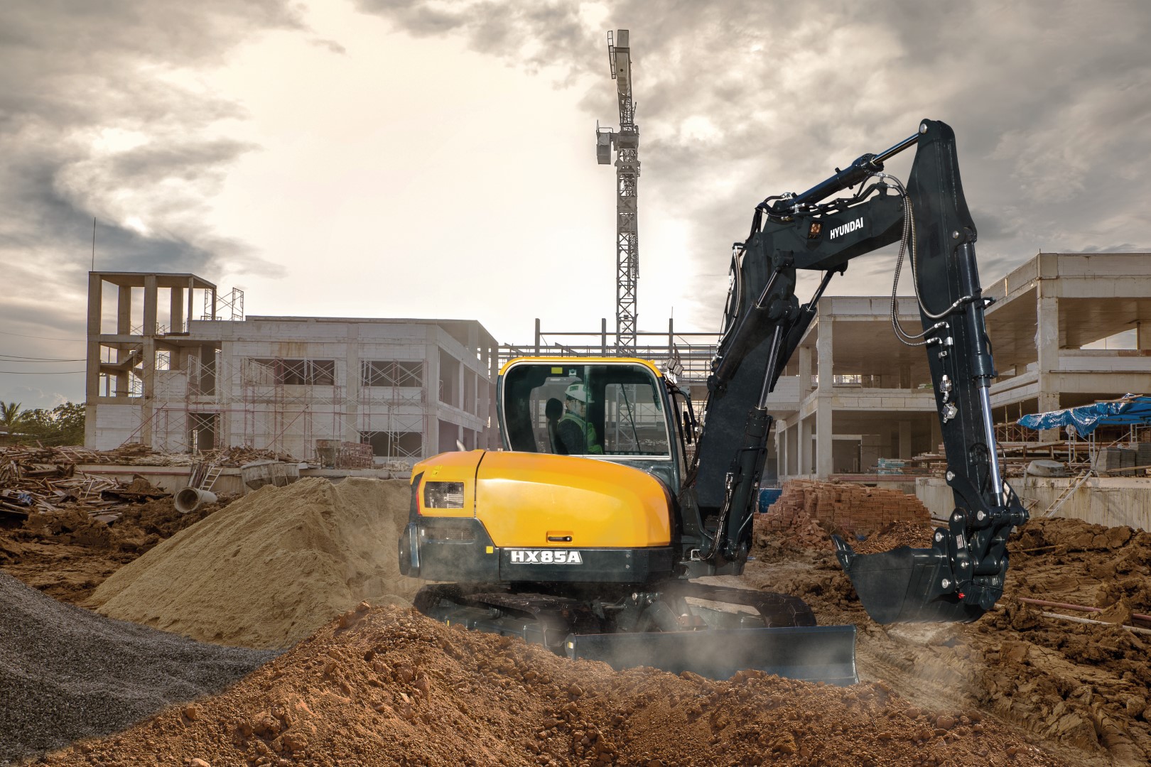 De HX85A compacte graafmachine maakt deel uit van de gloednieuwe A-serie van Hyundai: een nieuwe generatie bouwmachines die voldoet aan de Europese emissiestandaard Euro V. Maar hij heeft nog veel meer in petto! Terwijl aan de regelgeving is voldaan, streeft Hyundai naar een baanbrekend niveau in klanttevredenheid met maximale prestaties en productiviteit, meer veiligheid, meer gemak en een verbeterd uptimemanagement. Deze compact nieuwkomer in de power utility-klasse combineert een robuuste constructie met een uitstekende stabiliteit. Zeer veelzijdig en uitgerust met nieuwe elementen, creëert hij een wereld aan nieuwe mogelijkheden waarin kleine inspanningen bergen verzetten. Het is tijd om het Hyundai-effect te ervaren!