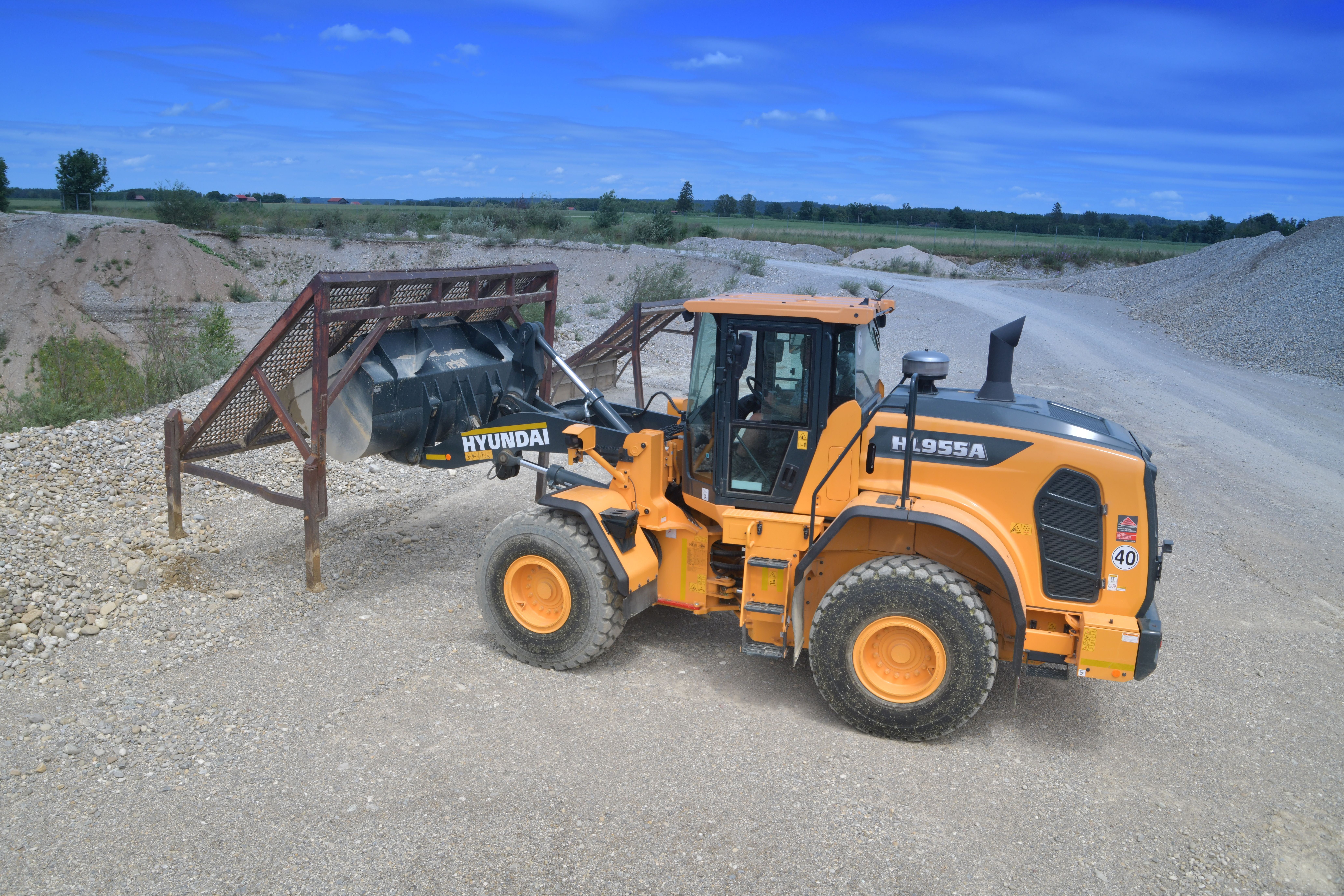 HYUNDAI HL955A WIELLADER Details kunnen een enorm verschil betekenen als het gaat om veiligheid, met name wanneer u onder zware omstandigheden werkt. Het draait niet enkel om het naleven van regels. De veiligheidsfuncties van de HL955A zijn ontworpen en getest om aan uw behoeften in de echte wereld te voldoen, en u beschikt zelfs over een extra paar ogen dankzij het optionele, geavanceerde rondomzichtsysteem (AAVM) en het intelligente detectiesysteem voor bewegende objecten (IMOD) en radarsystemen. Het vertrouwen wordt gesterkt door technieken die een gevoel van stabiliteit en soepele prestaties bieden bij zwaarbelast werk. Doordat deze wiellader voor een rustige, ongevalvrije werkplek zorgt, verhoogt hij de productiviteit en de gemoedsrust van elke machinist.